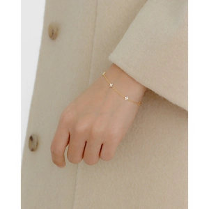 Detailed close-up of a gold-plated flower bracelet with sparkling zircons on a model's wrist