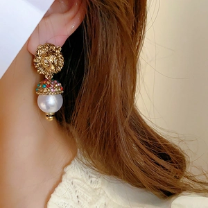 Detail of luxury lion head pearl earring with multi-colored crystals on model