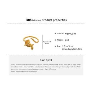 Detail view of gold three-layer snake ring showing copper material and glass stones