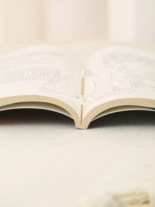 Vista macro di un ferma pagine in acrilico trasparente su un libro aperto per la lettura