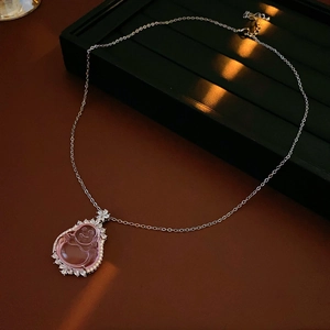 Macro shot of pink resin Buddha pendant with zircon crystals on a fine silver chain