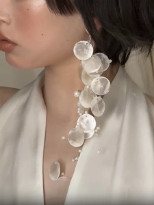 Detail of long tassel earrings featuring translucent shell discs and small white pearls