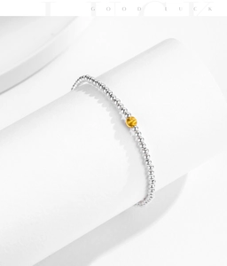 Close-up of s925 silver beaded bracelet with a brushed gold accent bead on white display