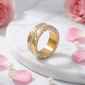 Macro shot of gold hammered wide band ring with inlaid crystals on marble tray