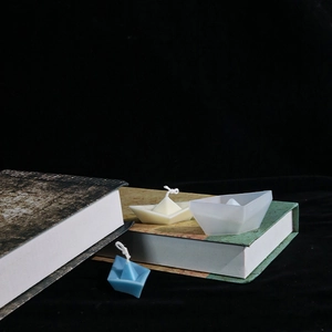 Minimalistische Duftkerzen in Papierbootform in Blau und Weiß auf Vintage-Büchern