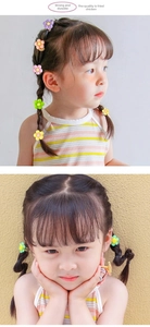 Close-up of colorful flower hair ties and clips on toddler pigtails for kids hair styling
