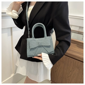 Close-up of stylish woven light blue handbag featuring a large decorative bow on the front