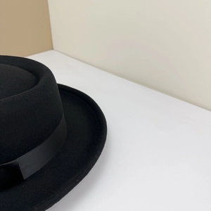Détail de la texture d'un chapeau en laine noire avec ruban gros-grain sophistiqué