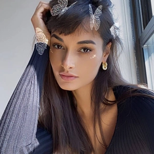 Sparkling butterfly hair clips and metal hoop earrings worn by a model in soft sunlight