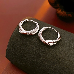 Detailed close-up of silver twisted hoop earrings with sparkling zircon inlay details