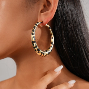 Golden geometric round hoop earrings with leopard print pattern worn by a model
