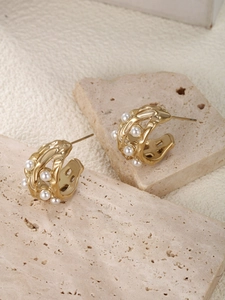 Detail of gold organic textured earrings featuring irregular pearls on a stone base