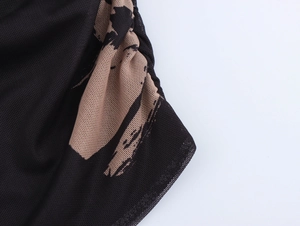 Dettaglio del tessuto a rete nero con stampa beige e design con cucitura a pieghe
