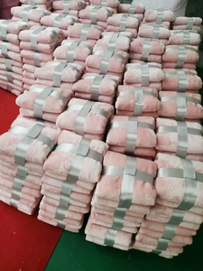 Pink coral fleece blanket detail with silver ribbon packaging in warehouse storage