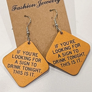 Détail de boucles d'oreilles en bois en losange avec citation drôle pour les fêtes