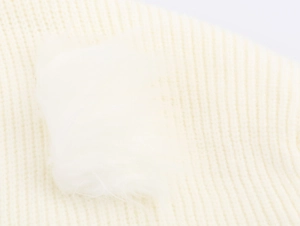 Detailaufnahme der cremefarbenen Stricktextur mit weichem Kunstfellbesatz am Ärmel