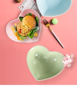 Top view of pink, blue and green heart-shaped ceramic dessert bowls in a food setting