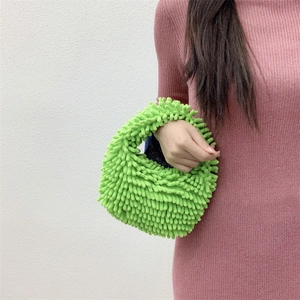 Close-up of vibrant green shaggy plush handbag held by model in pink dress