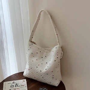 Dettaglio della borsa tote in maglia bianca con pois colorati ed etichetta Simple Wish