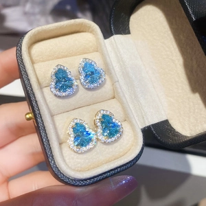 Gros plan de boucles d'oreilles gourde en zircon bleu étincelant dans un écrin cadeau