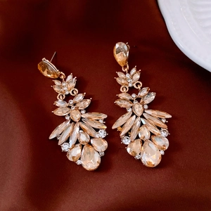 Detail view of champagne crystal tassel earrings on elegant dark coffee silk fabric