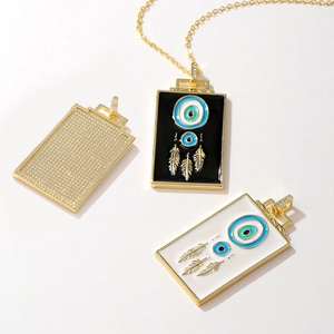Golden evil eye feather pendant necklace with black and white enamel drip on white background