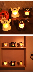 Detail of white and black ceramic ghost LED candles with polished finish for Halloween