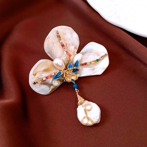 Detailed view of fan-shaped vintage brooch with baroque pearl and colorful zircon