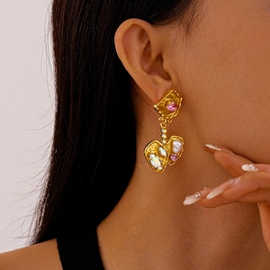 Close-up of vintage gold earrings with pink gemstones and pearls worn by a model