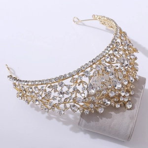 Luxurious bridal crown with gold metal leaf patterns and white rhinestones on velvet stand