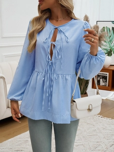 Detail view of blue striped blouse with tie-front design and stylish lantern sleeves