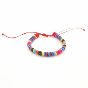 Detailed view of handmade bohemian woven surfing bracelet with colorful stripes on white background