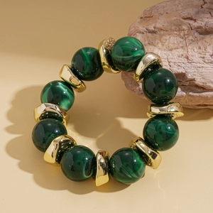 Dettaglio di perline marmorizzate verde scuro e distanziatori dorati su bracciale vintage
