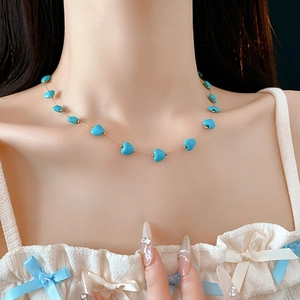 Close-up of heart turquoise beaded necklace with gold chain on model neck