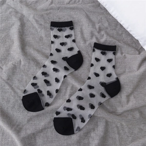Detail of grey sheer crew socks with black heart pattern and reinforced black toes