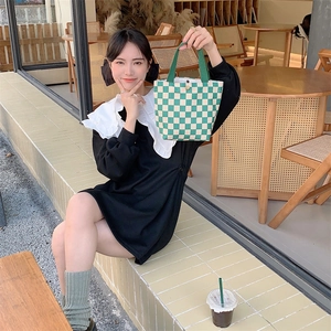 Detailed view of corduroy tote bag featuring green and white checkerboard pattern on a table
