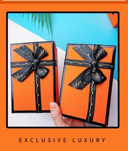 Close-up of bright orange luxury gift box with happy black ribbon bow detail