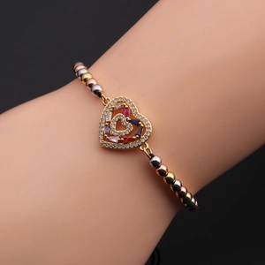 Detail view of heart charm bracelet with colorful zircons worn on a female wrist