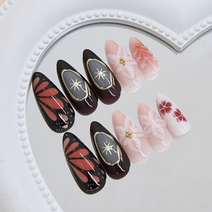 Elegant 24pcs almond press-on nails with lily motifs and gold starburst on a heart mirror