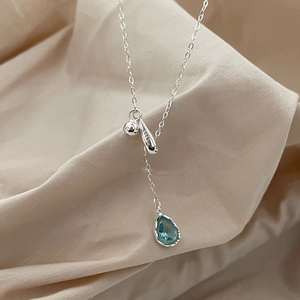 S925 sterling silver necklace with a blue teardrop pendant on beige fabric background
