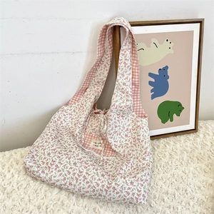 Detail of floral canvas tote bag featuring pink lining and decorative bow closure