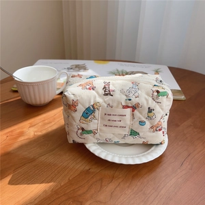 Detailed close-up of a quilted dog print cosmetic bag on a cozy wooden table setup