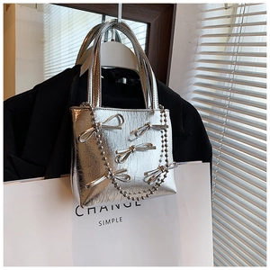 Silver handbag with bow details and metal chain hanging on a black hanger