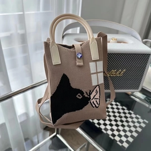 Détail du sac panda en tricot avec poignées tissées sur une table basse en verre