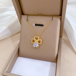Detailed shot of lucky clover necklace with inlaid crystals in a beige jewelry gift box