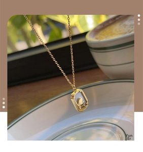 Detail of a rabbit shell pendant necklace shown against a cozy coffee cup setting
