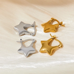Boucles d'oreilles étoile polies en or et argent sur un tissu de satin champagne