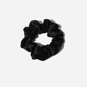 Detail of the soft satin fabric texture and pleated folds on a black scrunchie