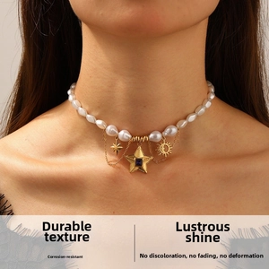 Detail shot of baroque pearl necklace with gold star pendants on female model neck