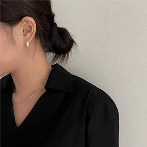 Close-up of minimalist textured silver hoop earrings and a ball chain necklace set